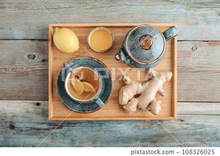 Ginger tea with lemon and honey in a blue cup on a bamboo tray 108326025