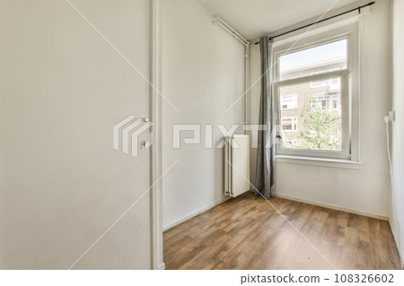 an empty room with wood flooring and a window in the corner that looks out to the cityscale 108326602