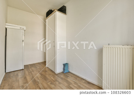 an empty room with wood floors and white walls, including a radiac heater on the right side an empty room with wood floors and white walls, including a radiac heater on the right side 108326603
