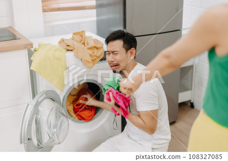 Funny man crying being force by his wife to wash clothes and do housework. 108327085