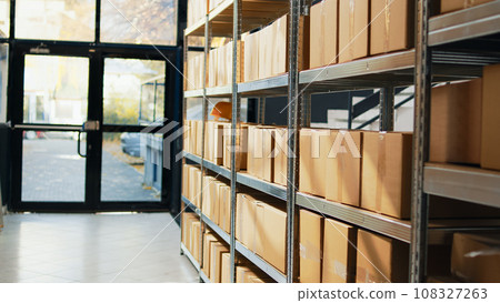 Empty storage room with packages on depot racks, containers and carton boxes prepared for stock distribution and order shipment. Warehouse space with retail store merchandise. 108327263