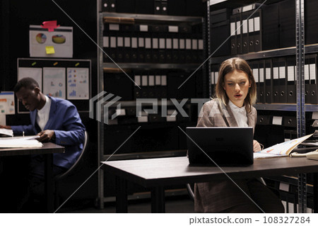 Caucasian inspector analyzing surveillance footage from victim house, working overtime at criminal case in arhive room. Private detective checking criminology report, trying to catch suspect 108327284