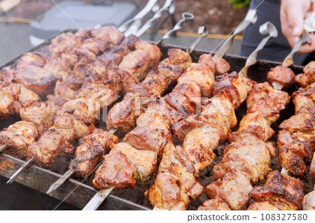 Traditionally cooked Turkish kebabs on skewers at hot grill, prepared outdoors in open air 108327580