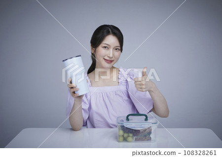 Image of a korean asain beautiful woman with a tumbler and plastic bucket fingers in motion. 108328261