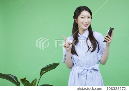 Quick Checkout_Picture of a korean asain beautiful woman posing with her finger holding a smartphone Image 108328272