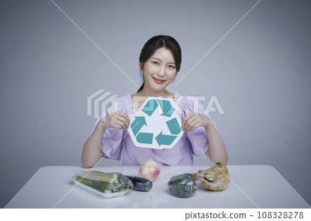 Image of a korean asain beautiful woman holding recycled fruit and vegetable labeling wrapped in zero-waste disposable wrap. Image of a korean asain beautiful woman holding recycled fruit and vegetable labeling wrapped in zero-waste disposable wrap. 108328278