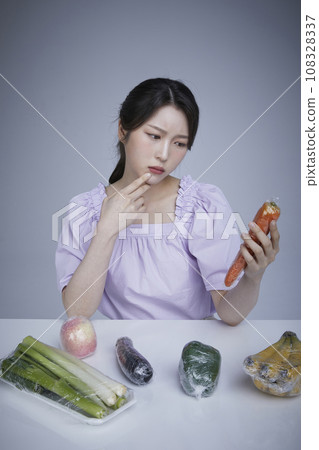 Plastic wrap_Picture image of a korean asain beautiful woman contemplating looking at plastic wrapped vegetables and vegetables fruits 108328337