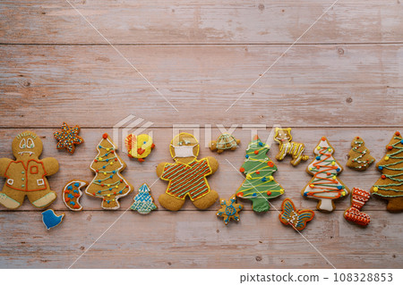 Colorful Christmas gingerbread cookies lie in a row on a light wooden background 108328853