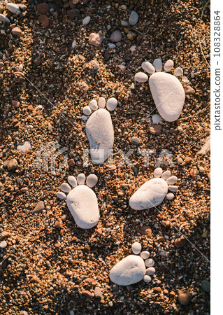 Chain of footprints of bare feet made of pebbles in the sand Chain of footprints of bare feet made of pebbles in the sand 108328864