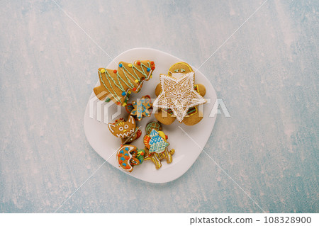 White plate with colorful gingerbread on a blue scratched background White plate with colorful gingerbread on a blue scratched background 108328900