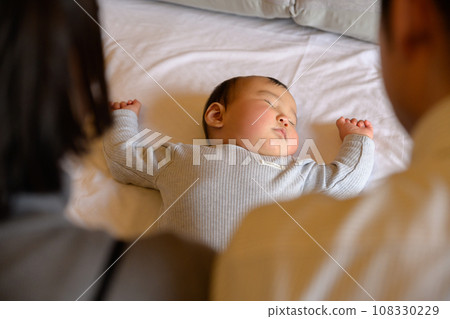 父親和母親看著熟睡嬰兒的睡臉，讓嬰兒上床，育嬰假，0 歲嬰兒 108330229
