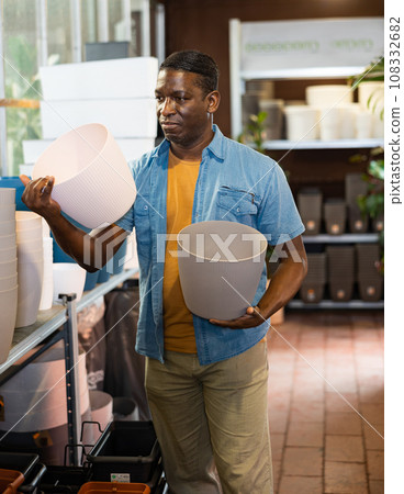 African american man chooses flower pots for indoor plants African american man chooses flower pots for indoor plants 108332682