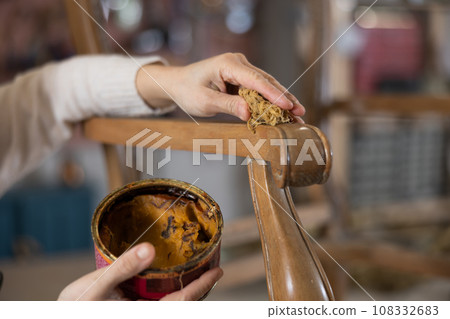 close-up of hands of craftsman who applies protective wax to carved wooden leg of antique chair close-up of hands of craftsman who applies protective wax to carved wooden leg of antique chair 108332683