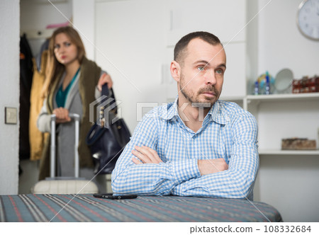 Frustrated man at table on background with woman leaving him Frustrated man at table on background with woman leaving him 108332684
