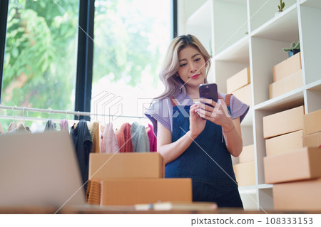 Starting small business entrepreneur of independent Asian female online seller talking on the phone with a customer and packing products for delivery to the customer. and SME delivery concept. Starting small business entrepreneur of independent Asian female online seller talking on the phone with a customer and packing products for delivery to the customer. and SME delivery concept. 108333153