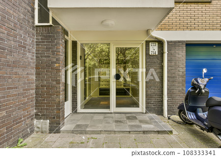 a blue motorcycle parked in front of a brick building with an open door on the left side and two windows to the right 108333341