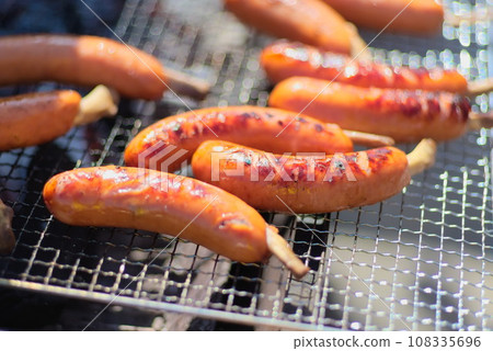 A large amount of frankfurters being baked on a wire mesh A large amount of frankfurters being baked on a wire mesh 108335696