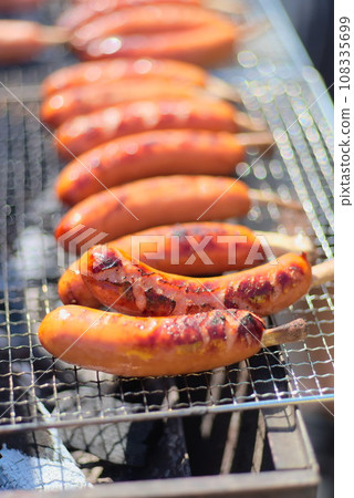 A large amount of frankfurters being baked on a wire mesh 108335699