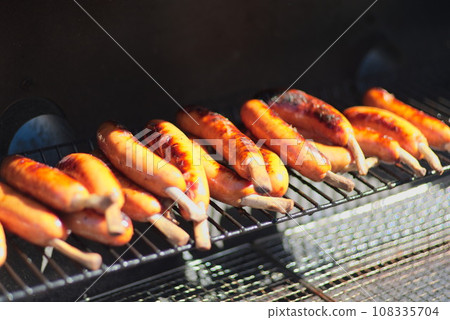 A large amount of frankfurters being baked on a wire mesh 108335704