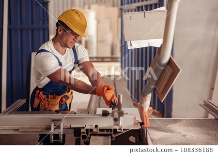 Serious male worker using woodworking machine in workshop 108336188