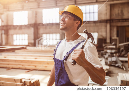 Cheerful builder with hammer working at construction site Cheerful builder with hammer working at construction site 108336197