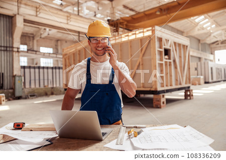 Cheerful male builder talking on cellphone at work Cheerful male builder talking on cellphone at work 108336209