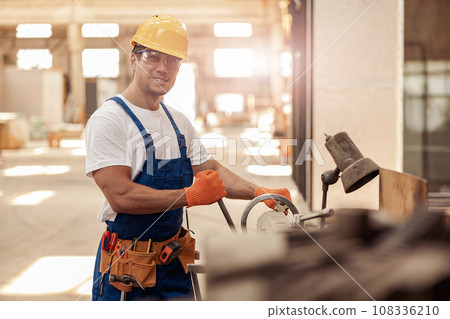 Cheerful male builder using professional equipment in workshop Cheerful male builder using professional equipment in workshop 108336210