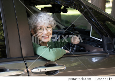 A senior woman peeking out of the driver's seat window 108336416