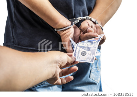 Arrested man with a handcuff on his hand giving money 108338535