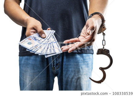 Arrested man with a handcuff on his hand holding money 108338539