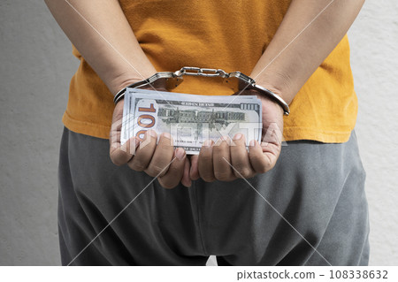Arrested man with a handcuff on his hand holding money Arrested man with a handcuff on his hand holding money 108338632