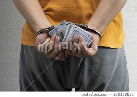 Arrested man with a handcuff on his hand holding money Arrested man with a handcuff on his hand holding money 108338633