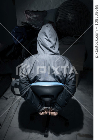 The man was sitting on a chair with tied hands in handcuffs The man was sitting on a chair with tied hands in handcuffs 108338669