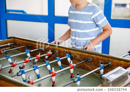 Close-up of kid boy playing table soccer. Happy excited child having fun with family game with siblings or friends. Positive kid. Close-up of kid boy playing table soccer. Happy excited child having fun with family game with siblings or friends. Positive kid. 108338744