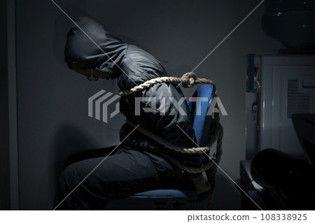 The man was sitting on a chair with tied hands in ropes 108338925