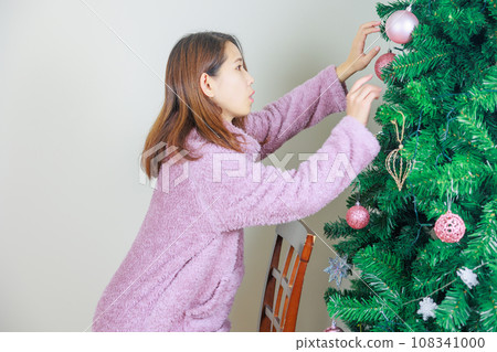 Woman decorating the Christmas tree Woman decorating the Christmas tree 108341000