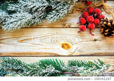 Wooden background frame with snowy fir tree branches, Christmas berries and fir cone. new year design, copy space Wooden background frame with snowy fir tree branches, Christmas berries and fir cone. new year design, copy space 108341287