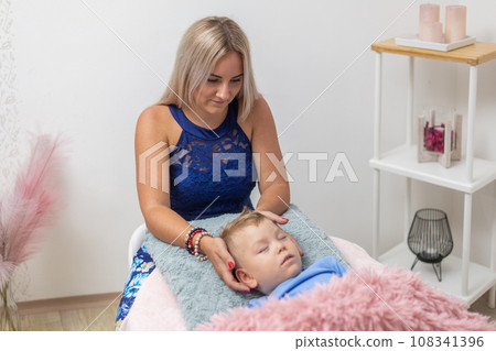Process of access or consciousness bars therapy, woman healing an young boy by method of 32 points on the head that we touch lightly in certain combinations, an alternative medicine 108341396