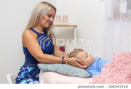 Woman healer performing access or consciousness bars to young boy, pseudoscientific method of alternative medicine that focuses on massaging various points on the head, an alternative medicine concept Woman healer performing access or consciousness bars to young boy, pseudoscientific method of alternative medicine that focuses on massaging various points on the head, an alternative medicine concept 108341410