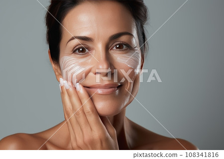 Skin beauty. Woman's head and shoulders, touching fresh, moisturized facial skin, applying toner, skin cream or lotion for a healthy look. 108341816