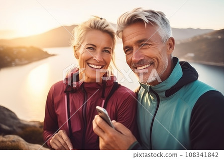 happy adult couple doing sports in the mountains and taking selfies on the phone, sharing photos on social networks, doing blogging 108341842