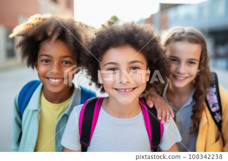 A group of happy cheerful active little children who are enjoying their studies at school meeting in the schoolyard, frolicking on the green grass, playing fun games, making new friends, hugging 108342238