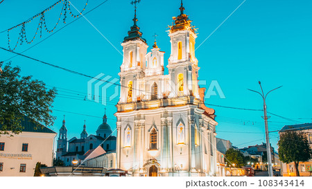 Vitebsk, Belarus. View On Church Of Resurrection Of Christ On Market Square In Evening Or Night Illuminations. Bold Colors. Famous Landmark. Travel Destinations. Traffic Car Lights Motion Vitebsk, Belarus. View On Church Of Resurrection Of Christ On Market Square In Evening Or Night Illuminations. Bold Colors. Famous Landmark. Travel Destinations. Traffic Car Lights Motion 108343414