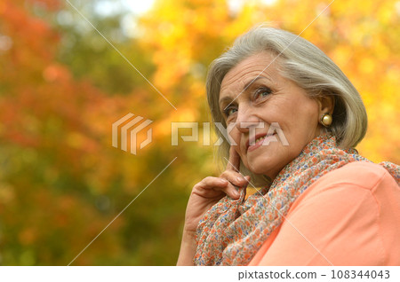 Senior woman walking in the park in autumn. Senior woman walking in the park in autumn. 108344043