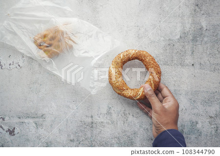 taking a Turkish Bagel Simit out from a plastic packet taking a Turkish Bagel Simit out from a plastic packet 108344790
