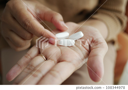 Close up of women hand taking pills Close up of women hand taking pills 108344978
