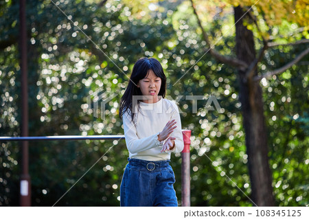 A state of an elementary school girl playing a horizontal bar in an autumn park A state of an elementary school girl playing a horizontal bar in an autumn park 108345125