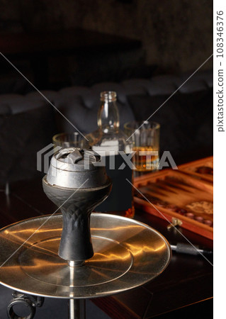 Hookah, bottle and glass of whiskey, backgammon board on table. 108346376