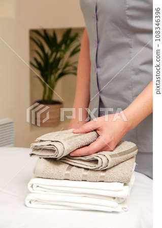Masseuse taking clean towels from pile, preparing to receive patient Masseuse taking clean towels from pile, preparing to receive patient 108346396