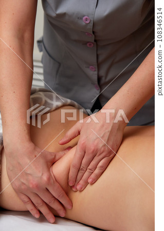 Professional massage therapist performing anti-cellulite waist massage to woman 108346514
